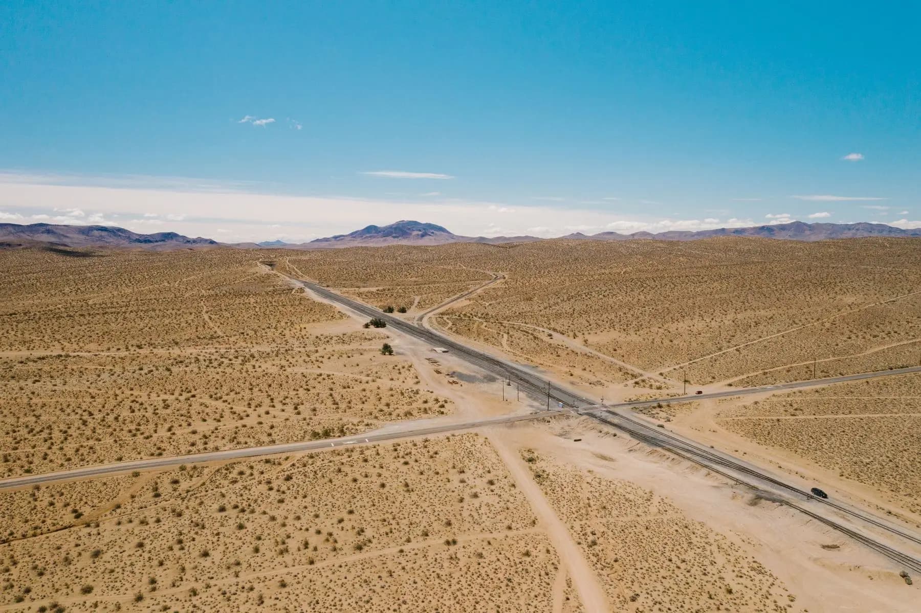 Open desert from the air, a road crossing toward distant ranges